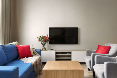 Стильный дизайн: гостиная комната в современном стиле с бежевыми стенами, светлым паркетным полом и телевизором на стене - последний тренд