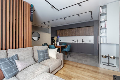 Стильный дизайн: большая открытая, объединенная гостиная комната в современном стиле с с книжными шкафами и полками, серыми стенами, полом из керамогранита, телевизором на стене и серым полом без камина - последний тренд
