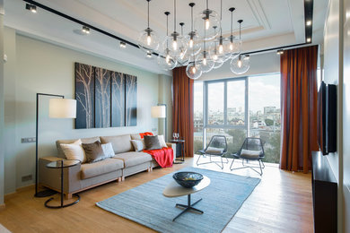 Стильный дизайн: парадная, открытая гостиная комната в современном стиле с телевизором на стене и светлым паркетным полом - последний тренд