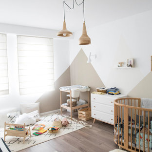 Diseño de habitación de bebé neutra escandinava con paredes blancas, suelo de madera oscura y suelo marrón