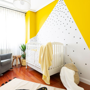 Ejemplo de habitación de bebé neutra costera con paredes multicolor y suelo de madera en tonos medios