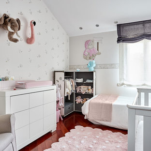 Diseño de habitación de bebé niña escandinava, de tamaño medio, con suelo de madera oscura, suelo marrón y paredes azules
