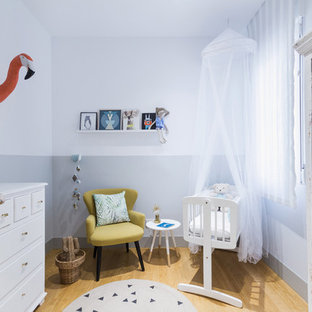 Modelo de habitación de bebé neutra escandinava, de tamaño medio, con paredes multicolor y suelo de madera clara