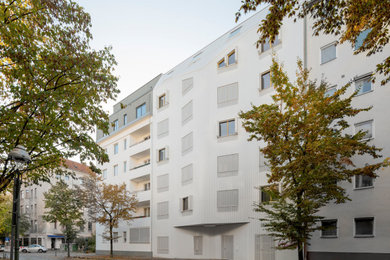 Großes, Dreistöckiges Modernes Haus mit Metallfassade, weißer Fassadenfarbe und Mansardendach in Berlin
