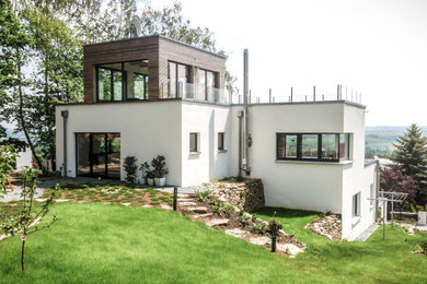 Mittelgroßes Modernes Einfamilienhaus mit Putzfassade, weißer Fassadenfarbe und Flachdach in Sonstige