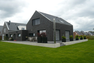 Großes, Zweistöckiges Modernes Einfamilienhaus mit Backsteinfassade, grauer Fassadenfarbe, Satteldach und Ziegeldach in Sonstige