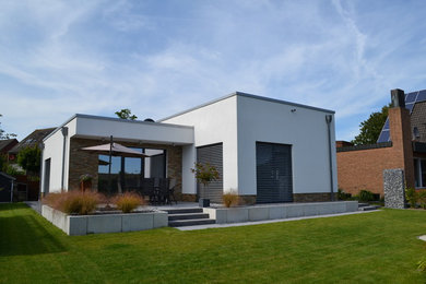Mittelgroßes, Einstöckiges Modernes Haus mit Putzfassade, weißer Fassadenfarbe und Flachdach in Sonstige