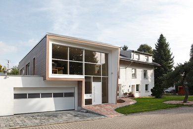 Cette photo montre une petite façade de maison marron tendance en bois à un étage avec un toit plat.