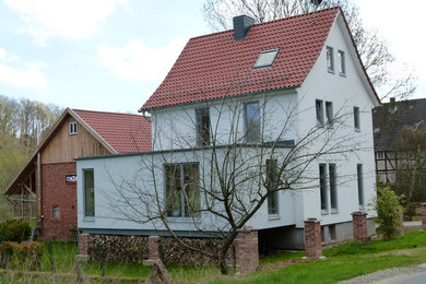 This is an example of a medium sized and white classic detached house in Hanover with three floors and a tiled roof.