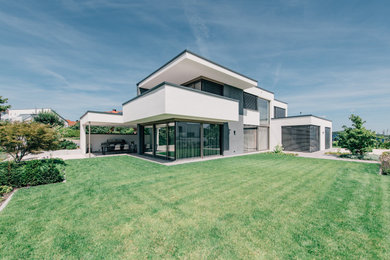 Imagen de fachada de casa blanca clásica de dos plantas con revestimiento de estuco, tejado plano y techo verde