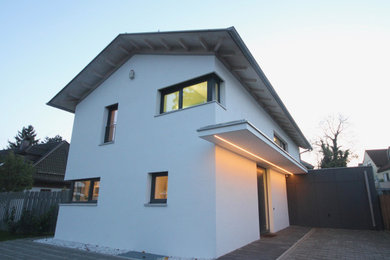 Mittelgroßes Modernes Einfamilienhaus mit Putzfassade, weißer Fassadenfarbe, Satteldach und Ziegeldach in München