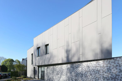 Modelo de fachada gris minimalista grande de dos plantas con revestimiento de aglomerado de cemento y tejado a dos aguas
