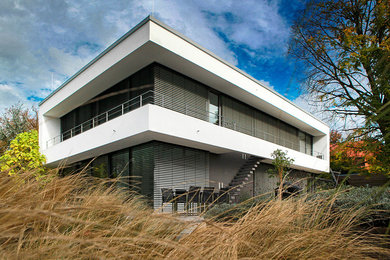 Diseño de fachada blanca actual grande de dos plantas con tejado plano y revestimientos combinados