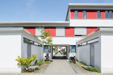 Zweistöckiges Modernes Reihenhaus mit Putzfassade, roter Fassadenfarbe und Flachdach in München