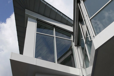 Idee per la facciata di una casa piccola bianca contemporanea a due piani con rivestimento in vetro e tetto piano