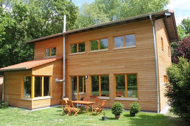 Diseño de fachada marrón actual de tamaño medio de dos plantas con revestimiento de madera y tejado a dos aguas