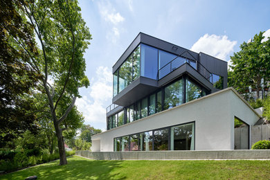 Ejemplo de fachada de casa gris minimalista grande de tres plantas con revestimiento de estuco, tejado plano y tejado de varios materiales