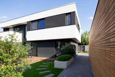 Diseño de fachada de casa negra contemporánea de dos plantas con revestimiento de estuco, tejado plano y techo verde