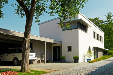 Mittelgroßes, Zweistöckiges Modernes Einfamilienhaus mit Putzfassade, weißer Fassadenfarbe und Flachdach in Stuttgart