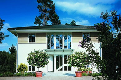Diseño de fachada contemporánea grande de dos plantas con revestimientos combinados y tejado a cuatro aguas