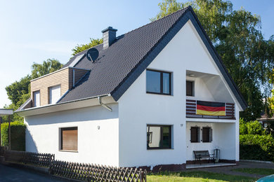 This is an example of a medium sized and brown contemporary two floor house exterior in Cologne with wood cladding and a pitched roof.