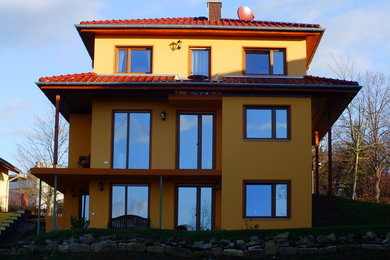 Large traditional yellow three-story stucco exterior home idea in Leipzig with a tile roof