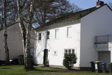 Modelo de fachada de casa blanca actual de tamaño medio de dos plantas con revestimiento de estuco y tejado de teja de barro