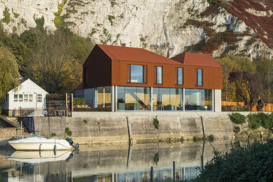 Cette photo montre une façade de maison marron tendance à un étage avec un revêtement mixte et un toit à quatre pans.