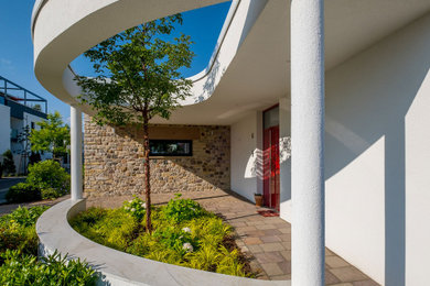 Mittelgroßes, Einstöckiges Modernes Einfamilienhaus mit Betonfassade, weißer Fassadenfarbe und Flachdach in Sonstige