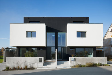 Großes, Dreistöckiges Modernes Haus mit Mix-Fassade, schwarzer Fassadenfarbe und Flachdach in Sonstige