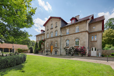 This is an example of an expansive and beige victorian house exterior in Hanover with three floors, stone cladding, a pitched roof and a tiled roof.