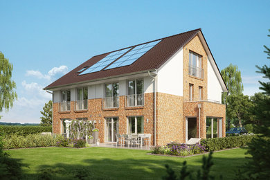 Modelo de fachada de casa bifamiliar beige tradicional grande de dos plantas con revestimiento de ladrillo, tejado a dos aguas y tejado de teja de barro