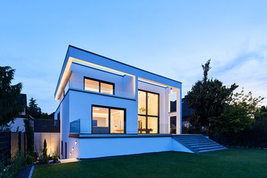 Mittelgroßes, Zweistöckiges Modernes Einfamilienhaus mit Putzfassade, weißer Fassadenfarbe und Flachdach in Düsseldorf