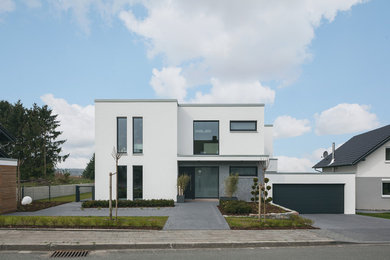 Mittelgroßes, Zweistöckiges Modernes Einfamilienhaus mit Putzfassade, weißer Fassadenfarbe und Flachdach in Dortmund