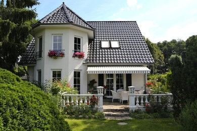 Ejemplo de fachada blanca tradicional de tamaño medio de dos plantas con revestimiento de estuco y tejado a dos aguas