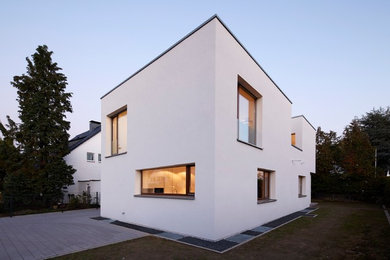 Kleines, Zweistöckiges Modernes Einfamilienhaus mit Putzfassade, weißer Fassadenfarbe und Flachdach in Düsseldorf