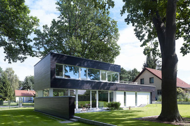 Mittelgroße, Zweistöckige Moderne Holzfassade Haus mit schwarzer Fassadenfarbe und Flachdach in Berlin
