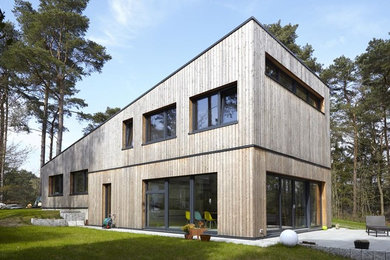 Inspiration for a brown and large contemporary two floor house exterior in Hamburg with wood cladding and a lean-to roof.
