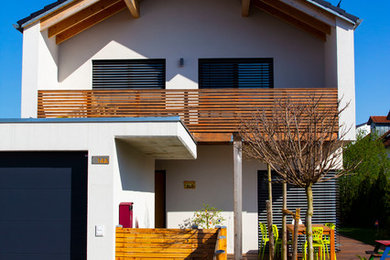 Foto de fachada de casa blanca minimalista de tamaño medio de dos plantas con revestimiento de estuco, tejado a dos aguas y tejado de teja de barro