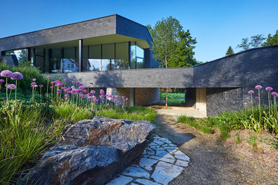Diseño de fachada de casa gris actual grande de dos plantas con revestimiento de piedra