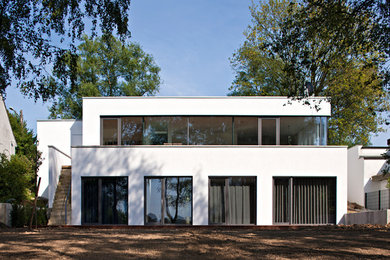 Zweistöckiges, Mittelgroßes Modernes Haus mit Putzfassade, weißer Fassadenfarbe und Flachdach in Düsseldorf