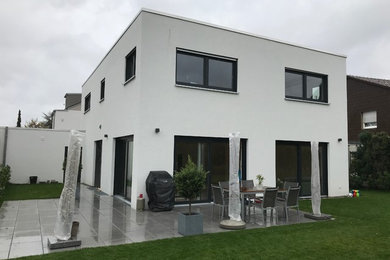 Zweistöckiges Modernes Einfamilienhaus mit Putzfassade, weißer Fassadenfarbe und Flachdach in Sonstige