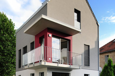 Modelo de fachada de casa gris contemporánea pequeña de tres plantas con revestimiento de estuco, tejado a dos aguas y tejado de teja de barro