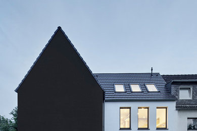Diseño de fachada de casa contemporánea pequeña de dos plantas con revestimiento de estuco, tejado a dos aguas y tejado de teja de barro