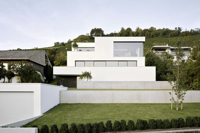 Modelo de fachada blanca contemporánea grande de tres plantas con tejado plano y revestimiento de estuco