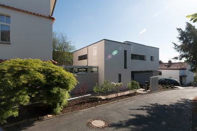This is an example of a small and gey contemporary two floor render detached house in Hanover with a flat roof.
