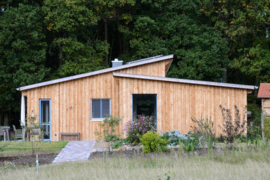 Diseño de fachada marrón rústica de tamaño medio de una planta con revestimiento de madera y tejado de un solo tendido