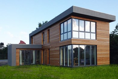 Diseño de fachada de casa negra contemporánea de tamaño medio de dos plantas con revestimiento de madera, tejado plano, tejado de varios materiales y tablilla