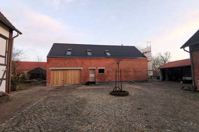 Ejemplo de fachada de casa roja y roja actual de tamaño medio de dos plantas con revestimiento de ladrillo, tejado a dos aguas, tejado de teja de barro y tablilla