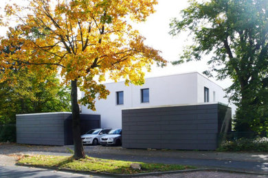 Modelo de fachada de casa bifamiliar blanca y negra actual de tamaño medio de dos plantas con revestimiento de estuco, tejado plano y tejado de varios materiales